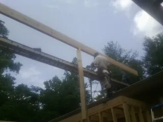 Carpenter setting a ridge beam over a new addition frame — Ice Dam Removal by Roofing Brothers in Colonial Beach