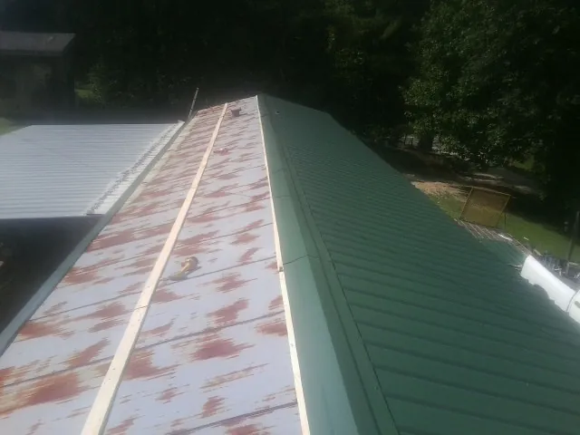 Old rusted panels beside newly installed green metal roofing — Wind Damage Roof Repair by Roofing Brothers in Colonial Beach