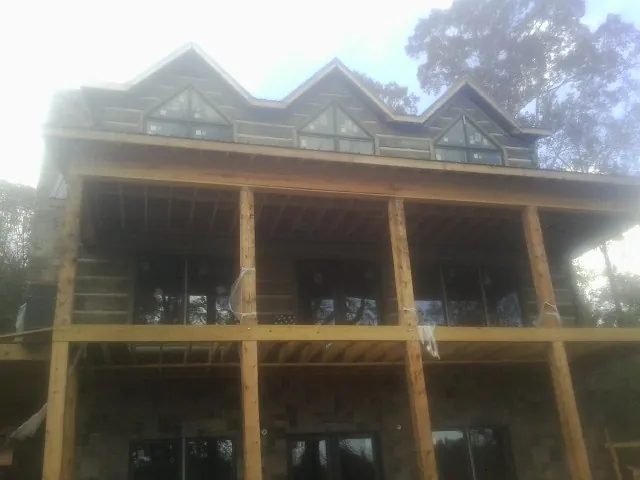Dormers and porch framing on a large log home under construction — Roof Coating work by our crew in Colonial Beach
