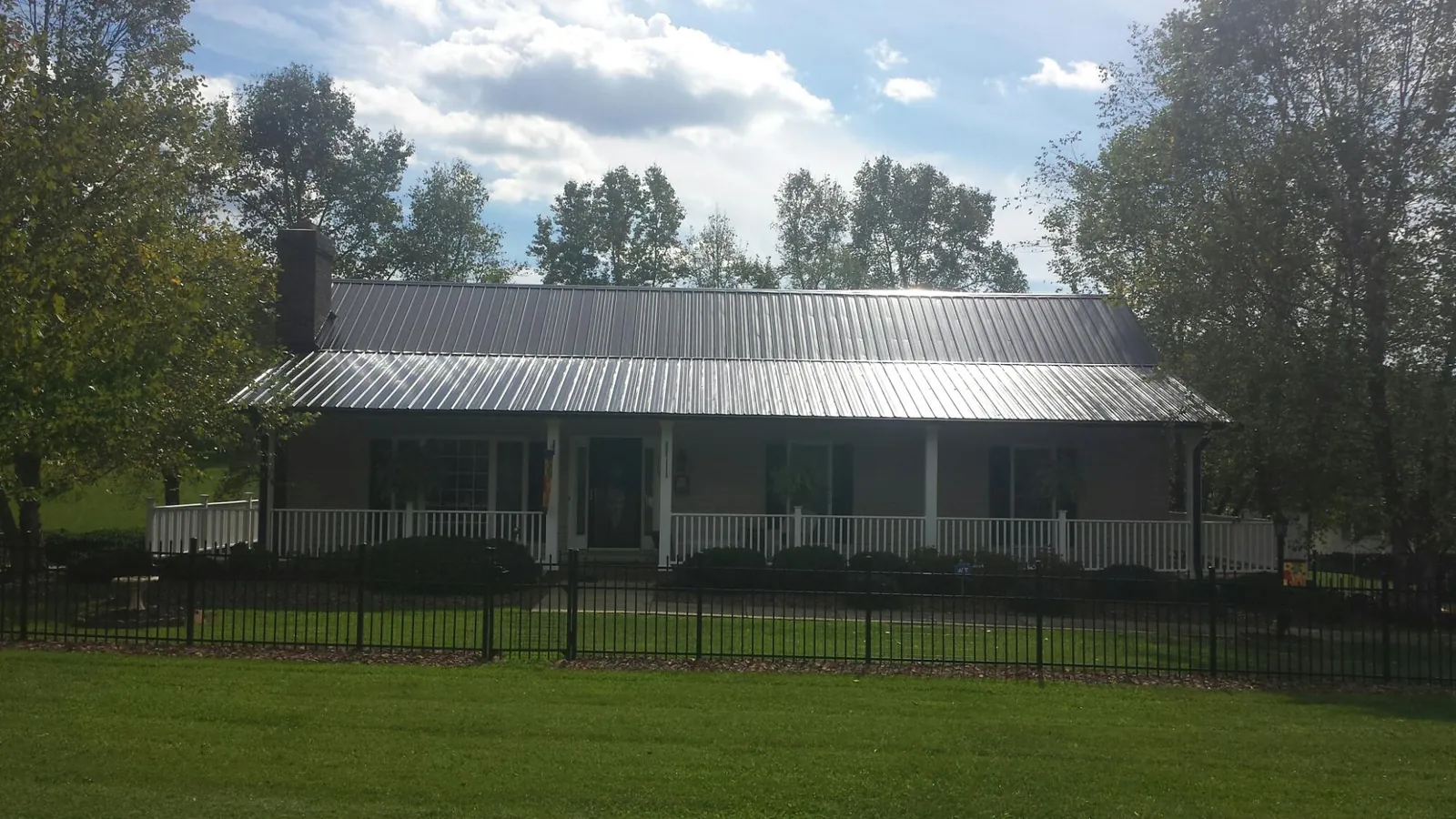 Gray metal roof on a brick ranch with a full width front porch — Gutter Guard Installation work by our crew in Colonial Beach