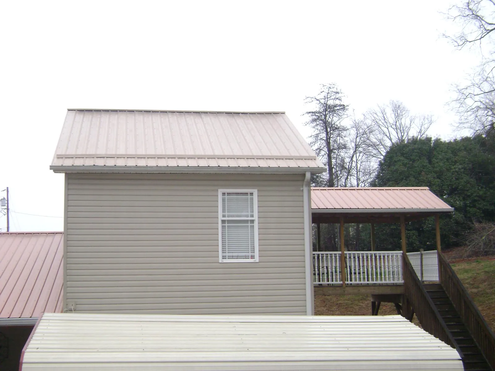 Tan metal roofs on a two story addition and attached porch, from a Roof Replacement job in Colonial Beach