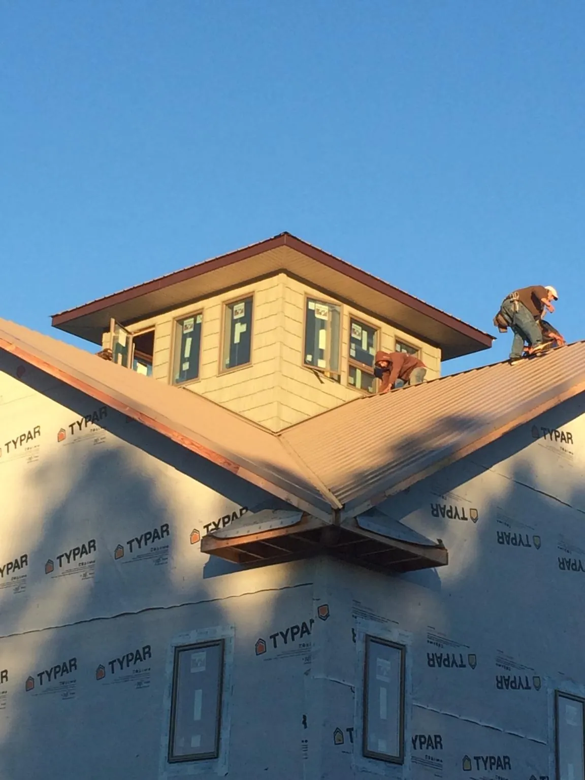 Roofers working around a rooftop cupola on a new metal roof at sunset — Roof Waterproofing in Colonial Beach by Roofing Brothers